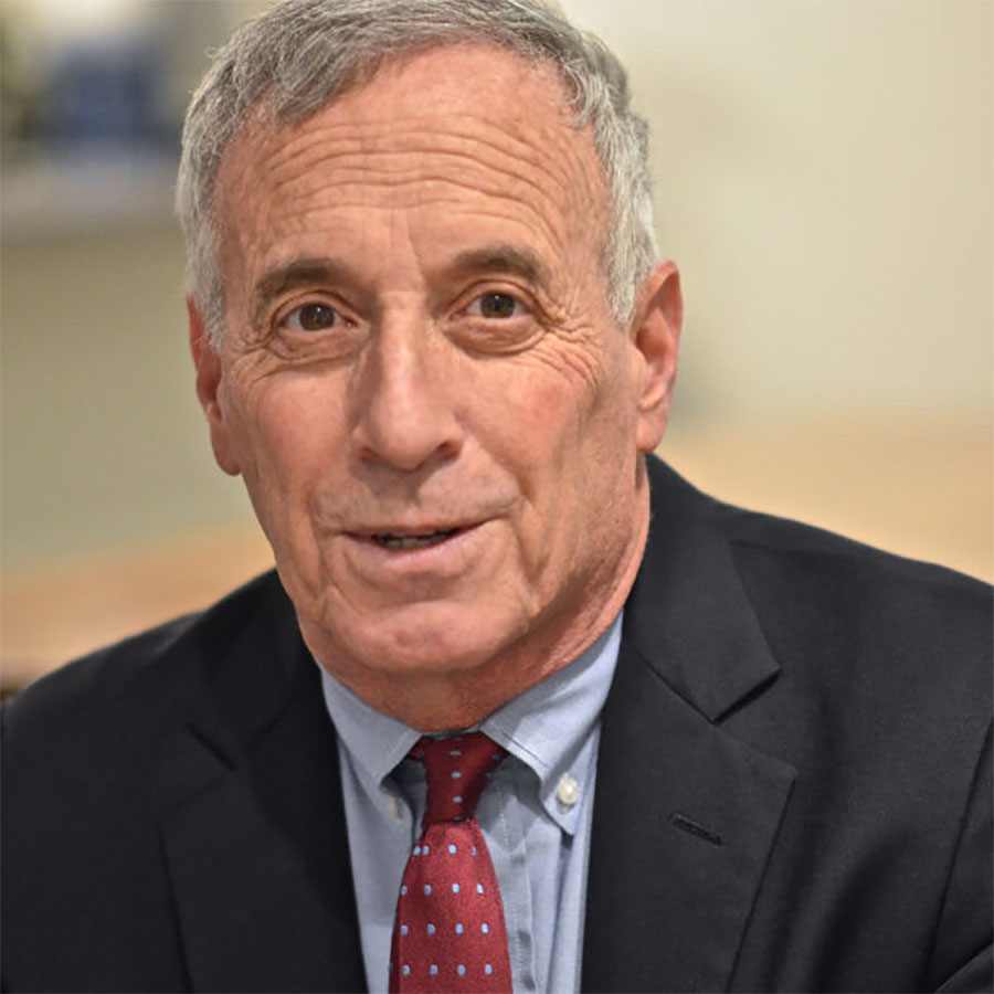 Headshot of Kotlikoff, who wears a dark suit jacket, red tie, and blue shirt. He is an older man with short gray hair, who smiles slightly.