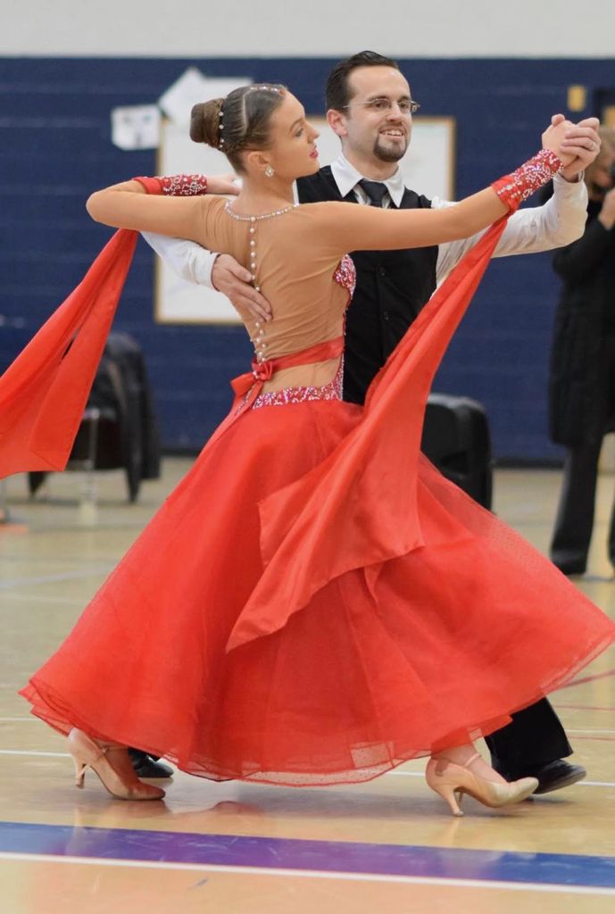 photo of Fiona Brymer had and her partner, Brian Freitas mid-dance. She wears a red dress and he wears black shirt and pants.