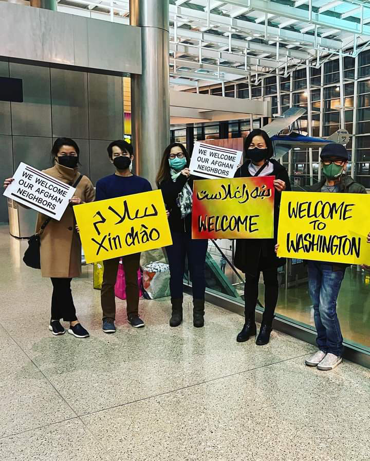 photo of Nathan Duong and a few members of his family at an airport holding welcome signs with English and Vietnamese writing