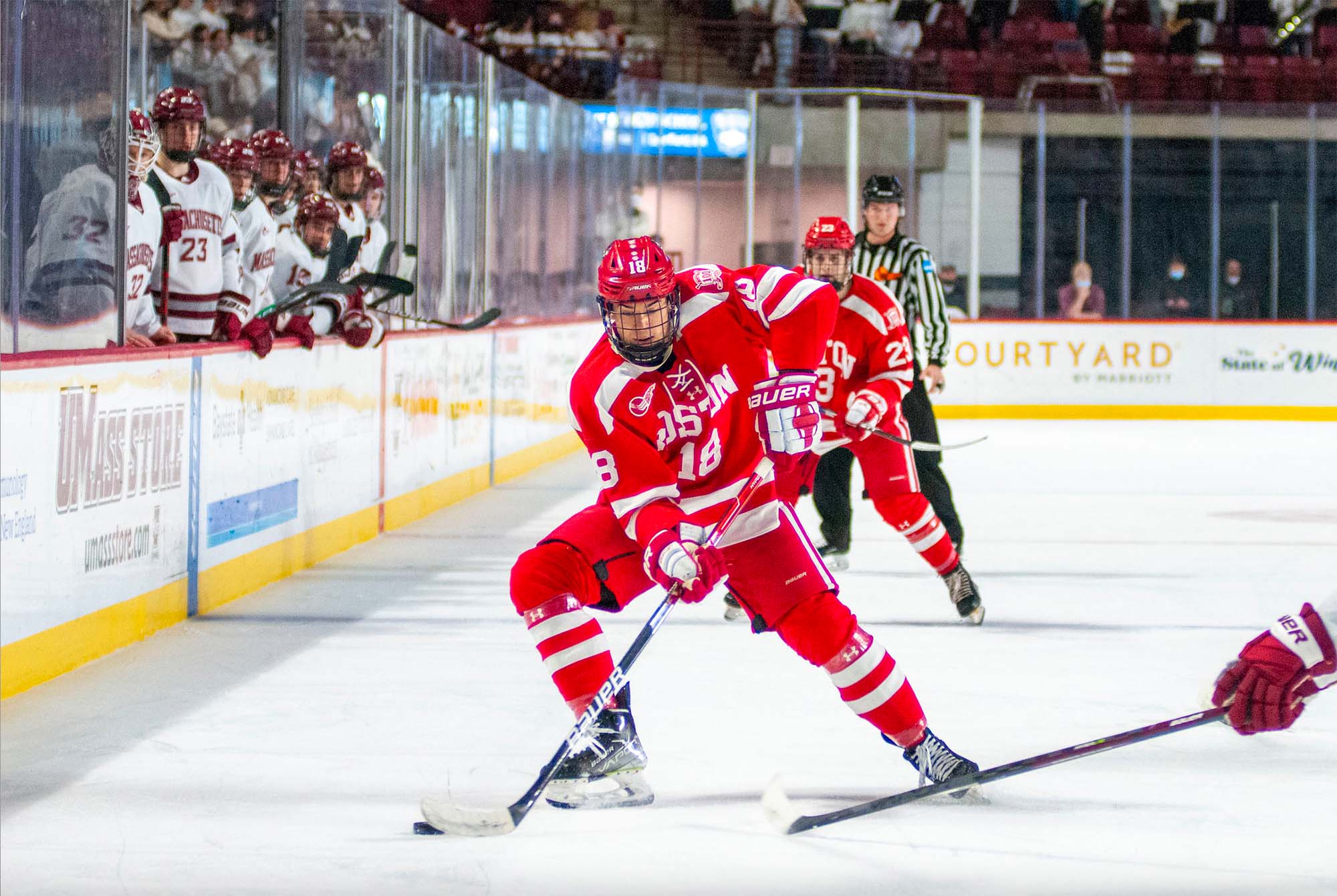 action shot of BU men's hockey player Jay O’Brien, a white man, mid game. He skates forward with the puck wearing his full hockey uniform