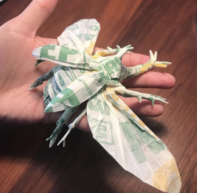 photo of a hand holding a large origami beetle crafted from Subway sandwich paper.