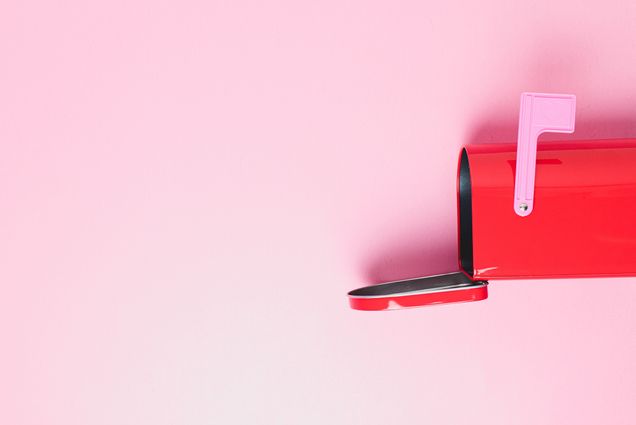 photo of an open, red mailbox on it's side on a bright pink background. It's pink flag is raised.