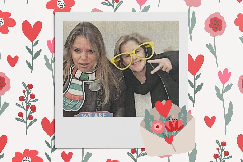 Image: Polaroid style photo of 2 white women, one wearing oversized yellow glasses and the other a prop scarf, as they make silly poses for the camera. Polaroid is placed on a tan background with a pattern of red, tan,  and pink flowers, red hearts, and a large envelope overflowing with various flowers