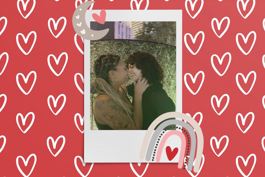 Image: Polaroid style photo of 2 women looking into each other eyes and laughing as they lean in for an almost kiss.Polaroid is placed on a red background with a pattern of white hearts. Clipart of a tan rainbow and moon are placed near the polaroid.