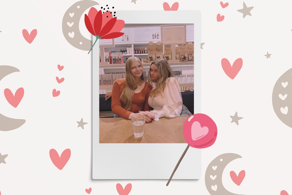 Image: Polaroid style photo of 2 women sitting in a cafe and leaning towards each other as they make silly faces at the camera. Polaroid is placed on a light tan background with a pattern of dark tan moons and pink hearts. A red flower and pink lollipop border polaroid.