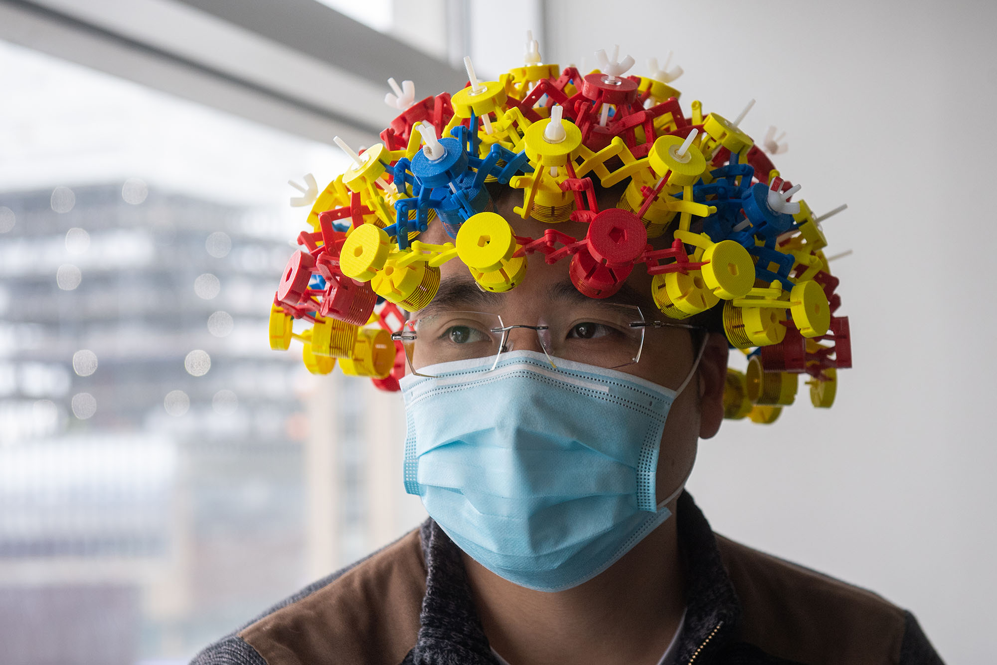 Photo of PhD student Ke Wu wearing a magnetic Metamaterial device. The hat is made of materials in red, yellow, and blue.