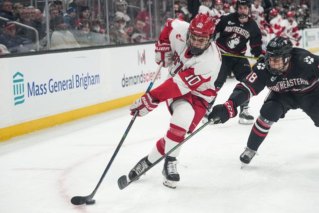 Photo of Nick Zabaneh (CAS’24) attacking against Northeastern’s Tyler Spott during the 69th Beanpot tournament championship game on February 14 at TD Garden. He skates forward with the puck as the Northeastern hockey player in a black uniform tries to intercept it.