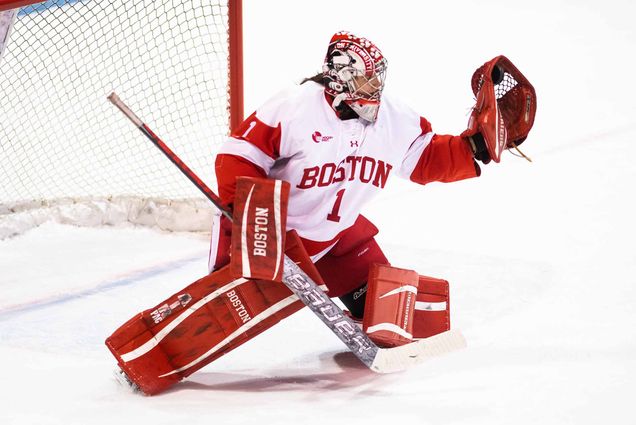 Photo of BU’s goalie Kate Stuart making a save during the women’s Beanpot Tournament at Matthews Arena on February 1, 2022. She extends her gloved right hand and turns her knees inwards.