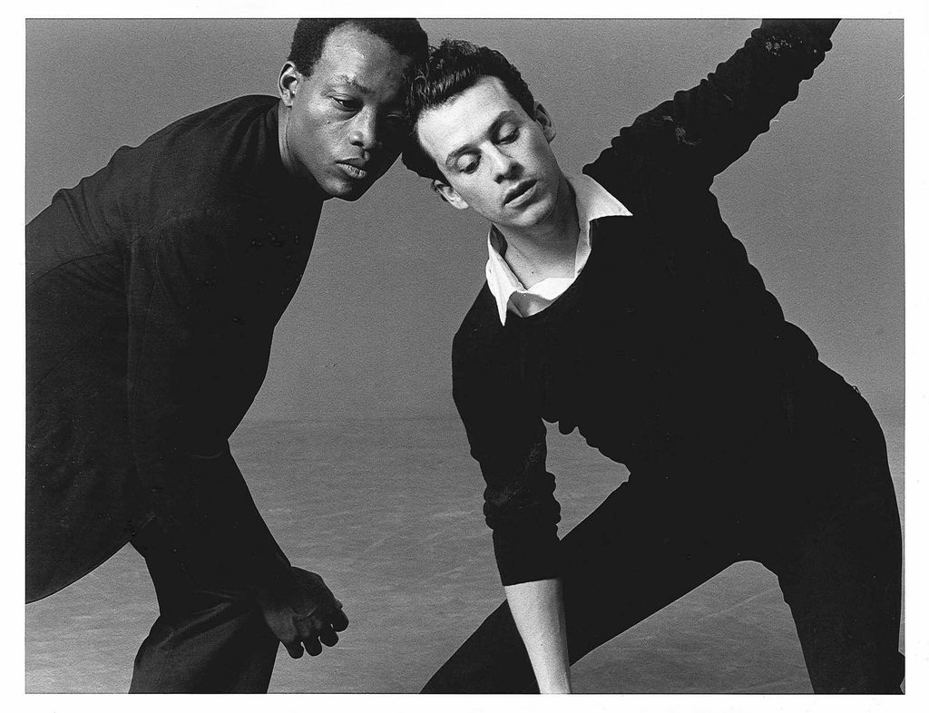 Black and white photo of Jones and his late partner Arnie Zane, who died from AIDS in 1988, in an undated image. The two formed the Bill T. Jones/Arnie Zane Dance Company in 1982. In the photo, the two looked focused as they lean towards each other. They both wear sweaters.