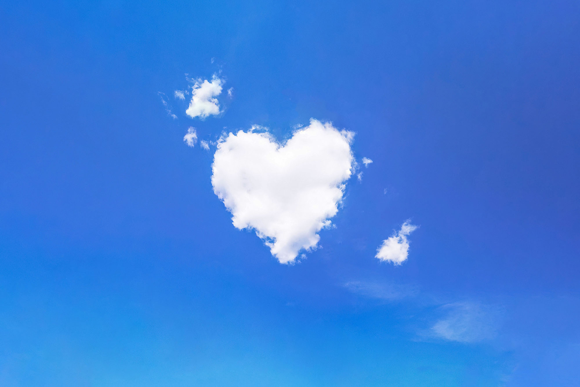 photo of a white, heart shaped cloud in a blue sky.