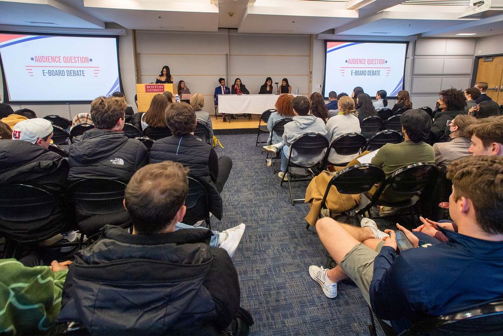 A large audience sits in front of a panel of student government members at Boston University in March 2022