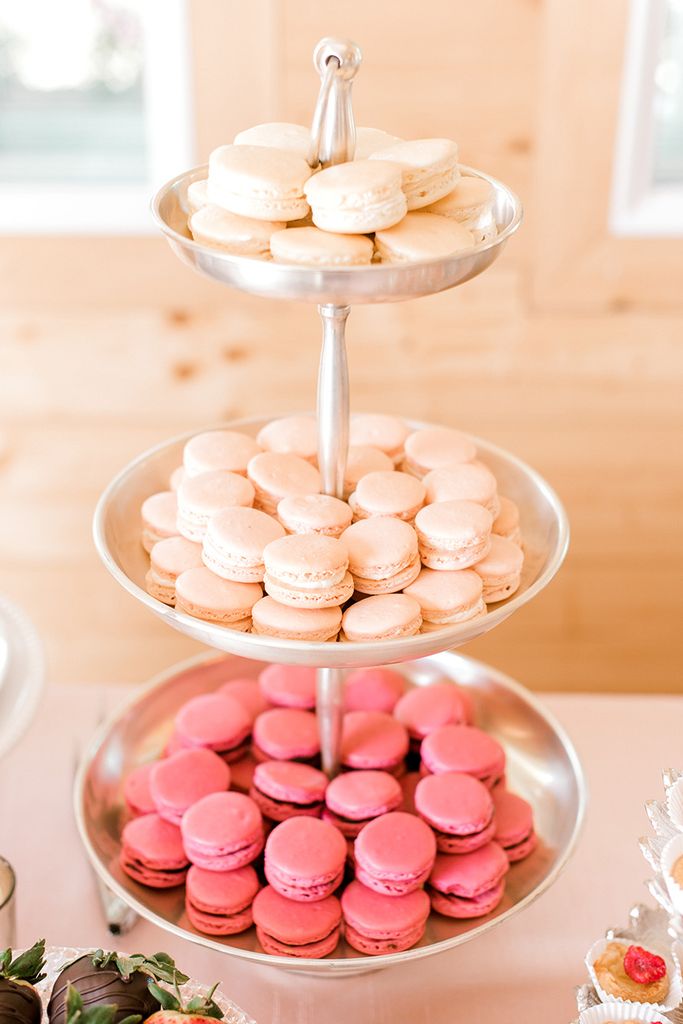 Photo of a tiered tray holding white champagne, pink raspberry rose, and tan dark chocolate cabernet macarons. Each color/flavor is arranged on its own tier.