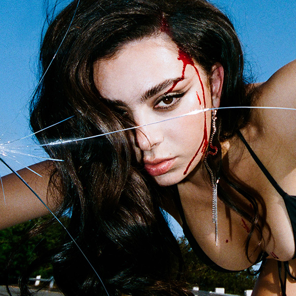 Charlie XCX album cover "crash". The image shows Charlie XCX, a white woman with dark hair wearing a black bikini swimsuit, on the hood of a car staring at the camera as if looking through a windshield. The windshield glass is cracked and the woman is bleeding from the forehead