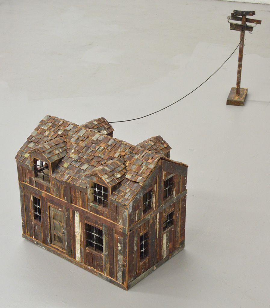 Image: Detailed sculpture of a house and mini telephone pole, both made of scraps of wood.