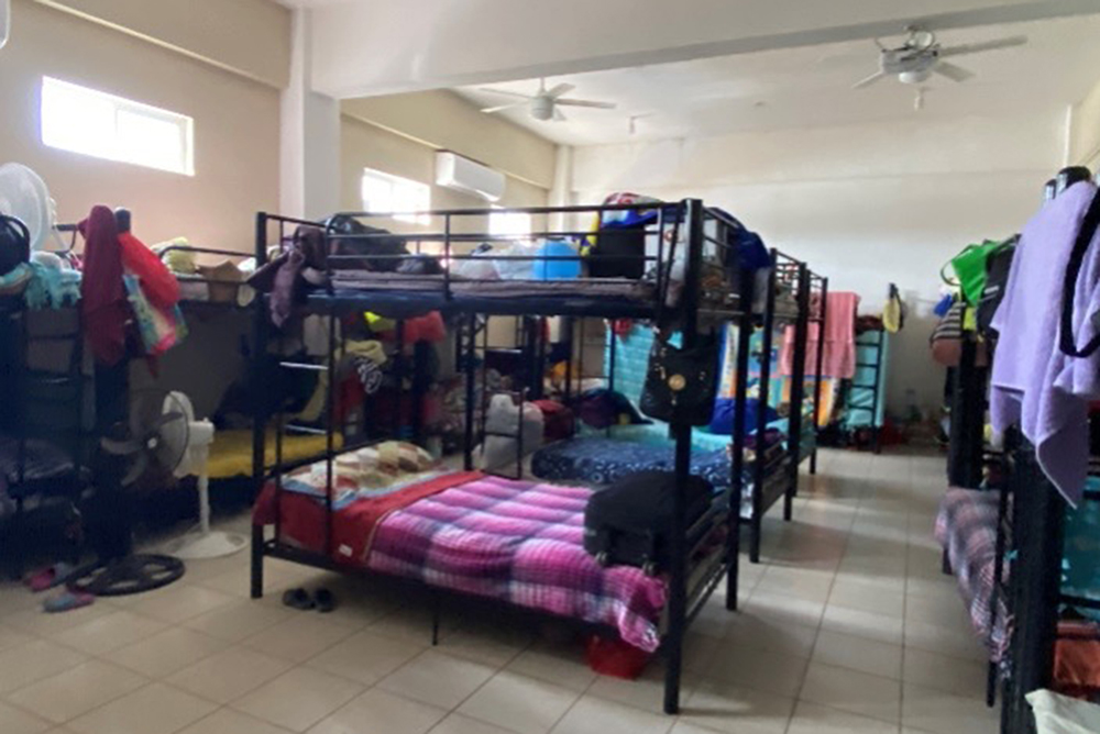 Photo of a bare room with various steel bunk beds throughout. Beds are made up with brightly colored blankets and gear.