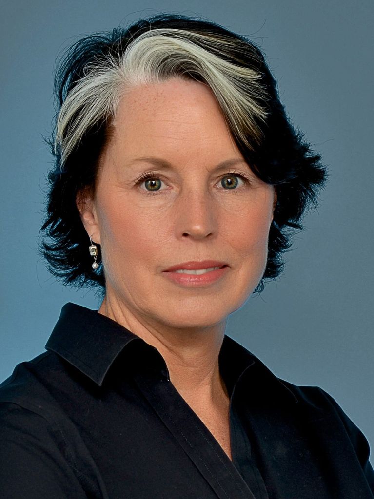 A picture of Kathleen Stone in front of a teal background