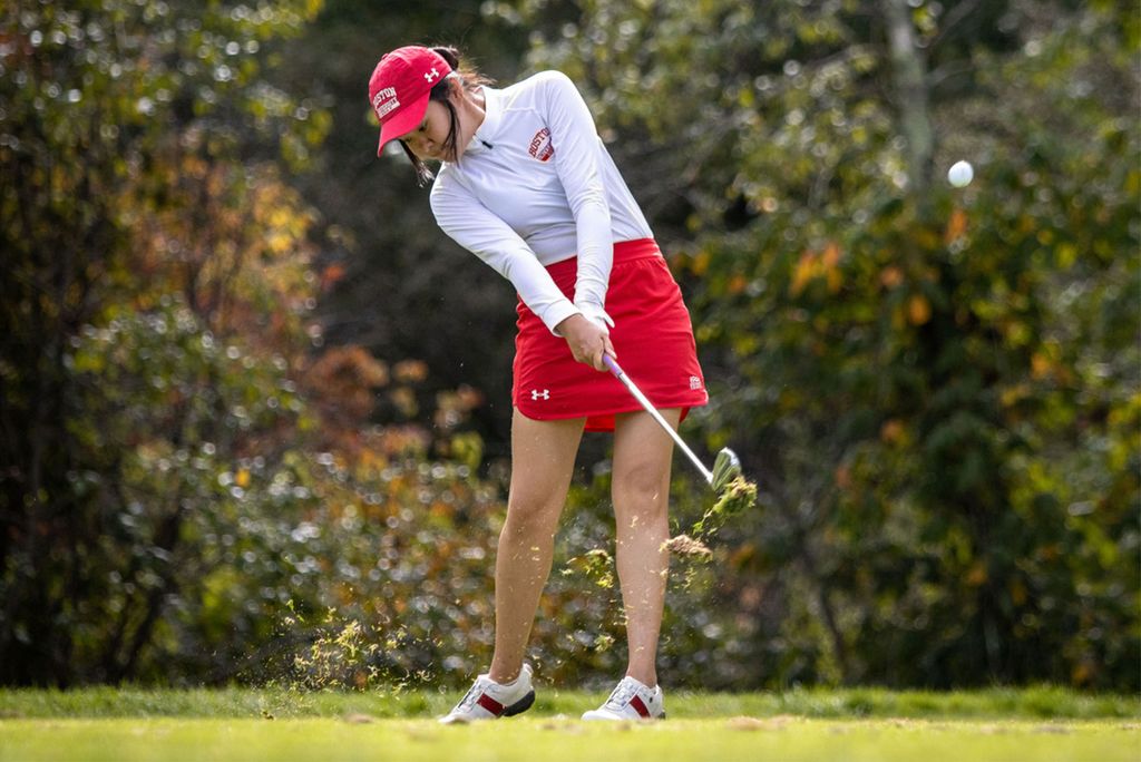 Hanako Kawasaki swings a golf club at the course in a red skirt and hat