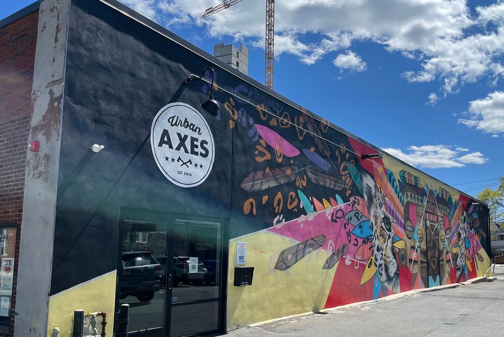 A photo of Urban Axes in Somerville, with a colorful mural on the side of a warehoues