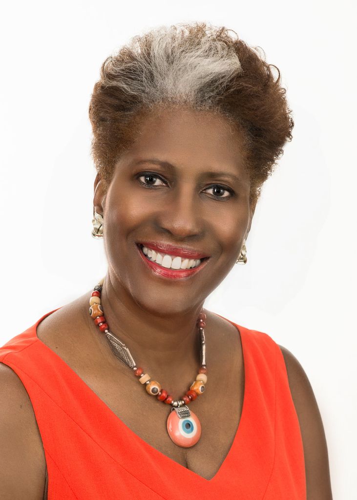 Headshot of Diane Kern (CAS’76) in a bright pink blouse and colorful necklace. She has a streak of white in her dark hair and smiles welcomingly.