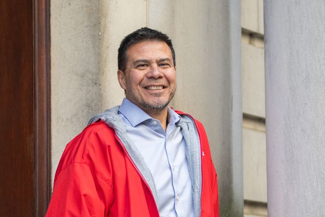 Jorge Delva wearing a red jacket and a blue shirt with a smile