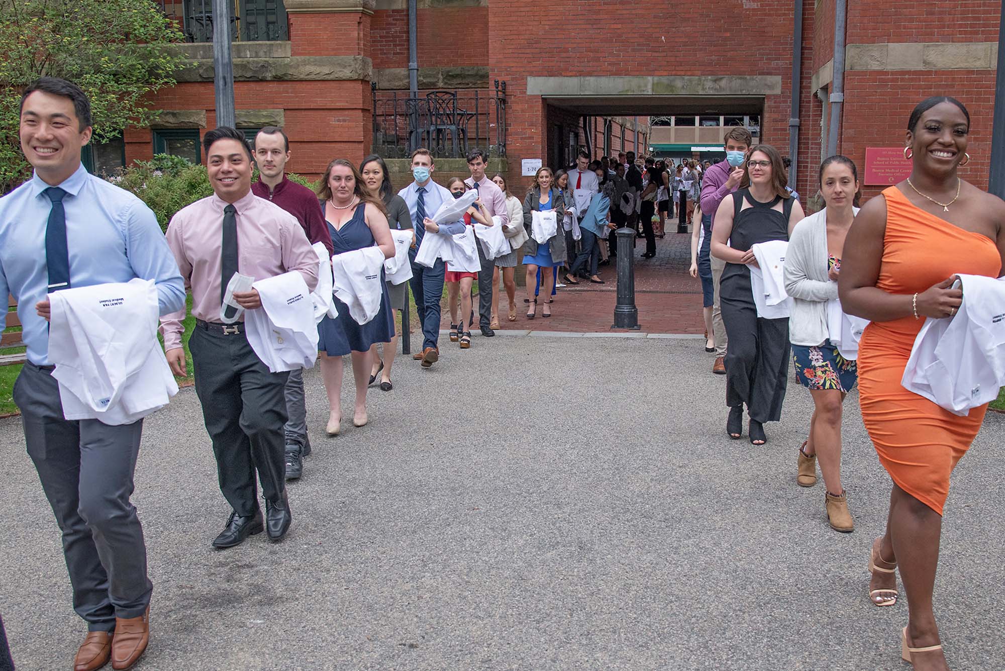 Coats over their arms, third-year medical students filing into a tent on the BU Medical Campus Talbot Green Monday for their in-person White Coat Ceremony. They’d had a pandemic-mandated virtual ceremony in August 2020, and Monday’s in-person ceremony was timed to coincide with the beginning of their third year, when their studies transition to clinical rotation.