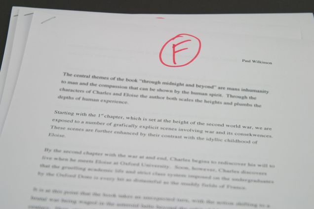 Photo of a stack of essays, the topmost essay has a grade, F, written at the top in red pen.