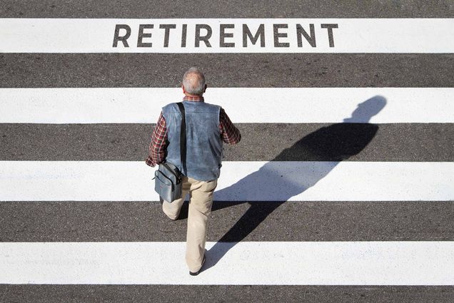 Photo of an older person who is slightly balding and has white hair walking down a street with large white stripes painted on it. One of the stripes at the top reads “Retirement.” The man, seen from above and behind, wears a vest and flannel and carriers a bag over his shoulder.