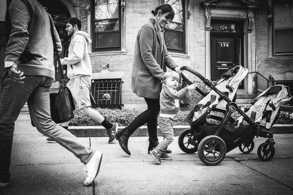 Griffin, a small child, wants a turn pushing his stroller down Bay State Road.