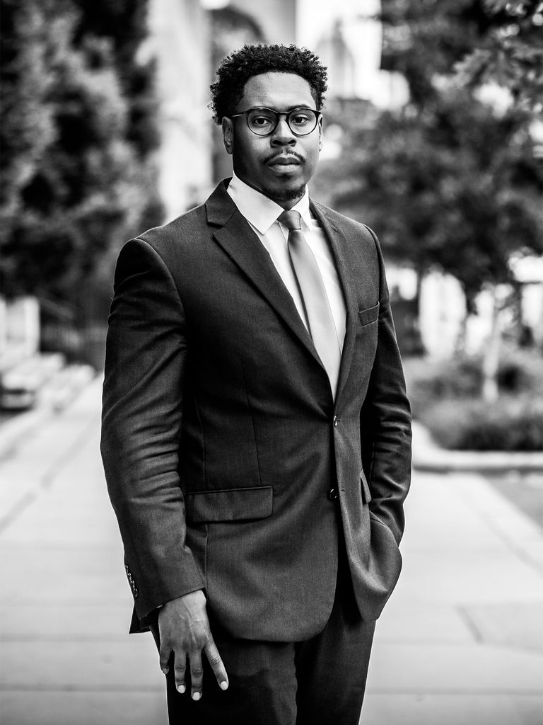 Moddie Linen stands outside in a suit with one hand pocketed in this black and white photo