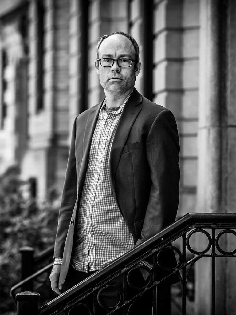 Spencer Piston stands on a stoop and looks at the camera in this black and white photo