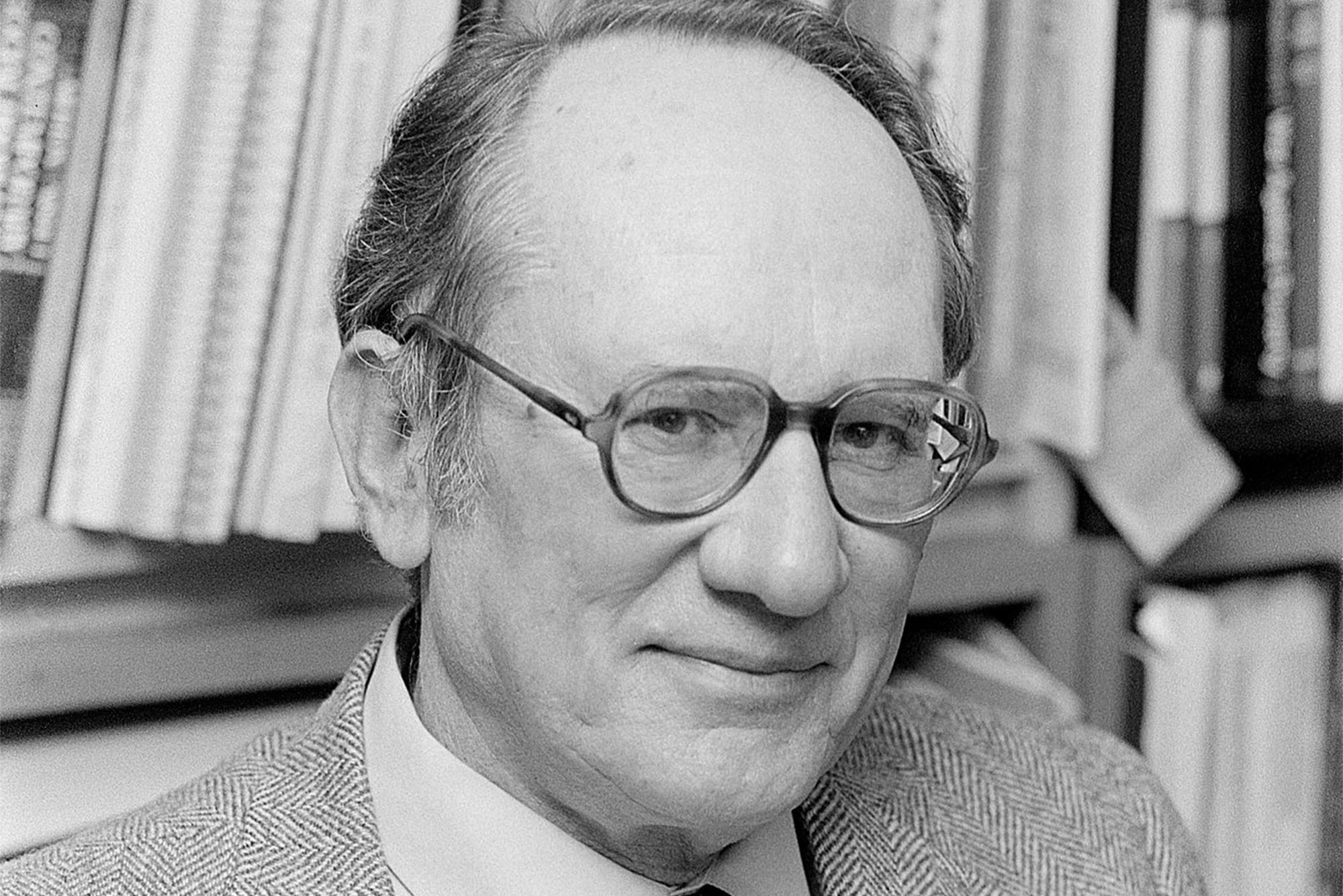 a portrait of Seymour Miller in black and white wearing glasses and a suit and tie