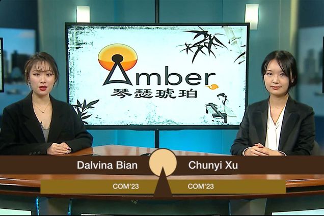 Screenshot of BUTV10 program Amber. Two young AAPI women wear black blazers and sit behind a news desk. At left, is Dalvina Bian, COM'23, who has brown hair and wears red lipstick. At right is Chunyi Xu, COM'23, who has black hair and smiles slightly. Behind them, on screen, a TV reads "Amber" in English and presumably in Chinese characters. The "A" of Amber is a broadcast towere and the design also features the figure of a chinese women in the lower right.