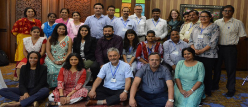 Photo of the RANI project team meeting with local stakeholders from the beginning of their planning phase. Yilma, seated at the bottom left corner, sits with a group of sitting and standing Indian stakeholders wearing badges. 