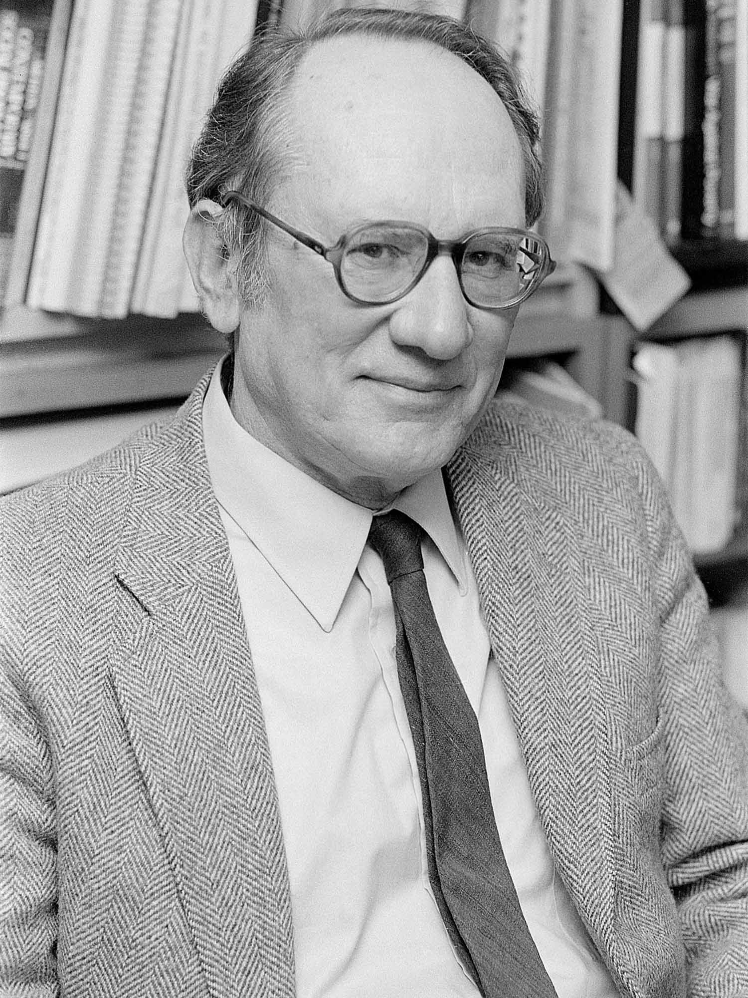 a portrait of Seymour Miller in black and white wearing glasses and a suit and tie