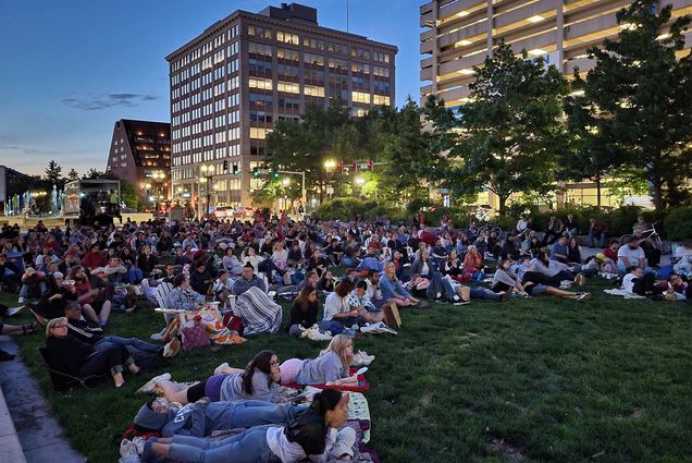 A large group of people gathered to watch a movie on the Rose Kennedy Greenway in Boston MA on a summer evening
