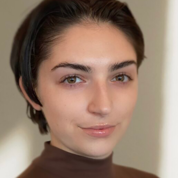 Photo of Leyla Tonak, a young light skinned woman with short black hair and wearing a brown turtleneck.