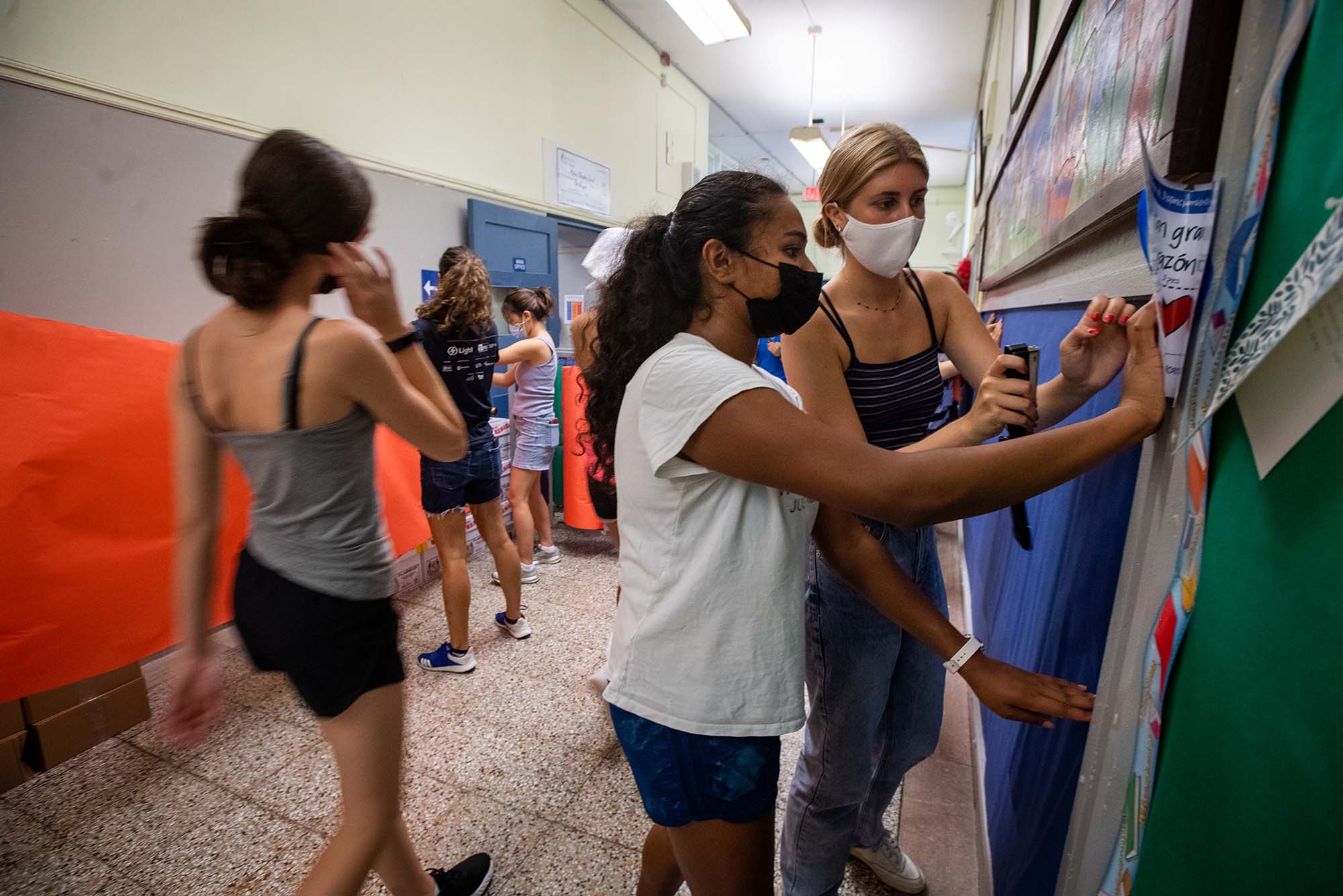 Photo of First-Year Student Outreach Project (FYSOP) participants Ananya Gupta (CAS’25), center, and Allie Richter (COM’25) right, working together to mount paper on the walls for use as bulletin boards at Mather Elementary in Dorchester.