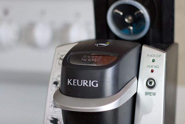 Image: Close up photo of a black Keurig coffee machine with its top open for beverage pods.