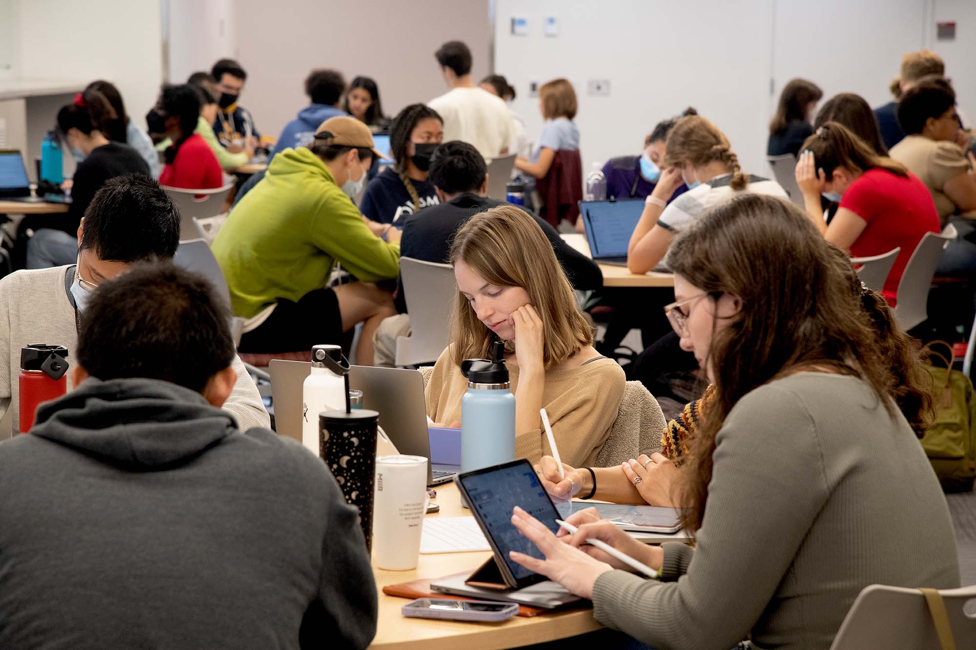 Photo of a “flipped classroom” approach, where medical students are given a problem that they research on their own, self-test to assess their knowledge, then come into the Learning Center to work on it with their team. Groups of students sit around large tables as they work together.