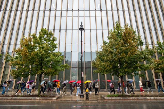 Umbrellas add a touch of color to a dreary Thursday, as Terriers wend their way past the Kilachand Center for Life Sciences & Engineering. Rain dumped nearly an inch on Boston, and Friday is expected to be much cooler, with a high of only 60. Could be fall has arrived. September 22 photo by Cydney Scott. Students walk in front of a large modern building with umbrellas in rainy weather