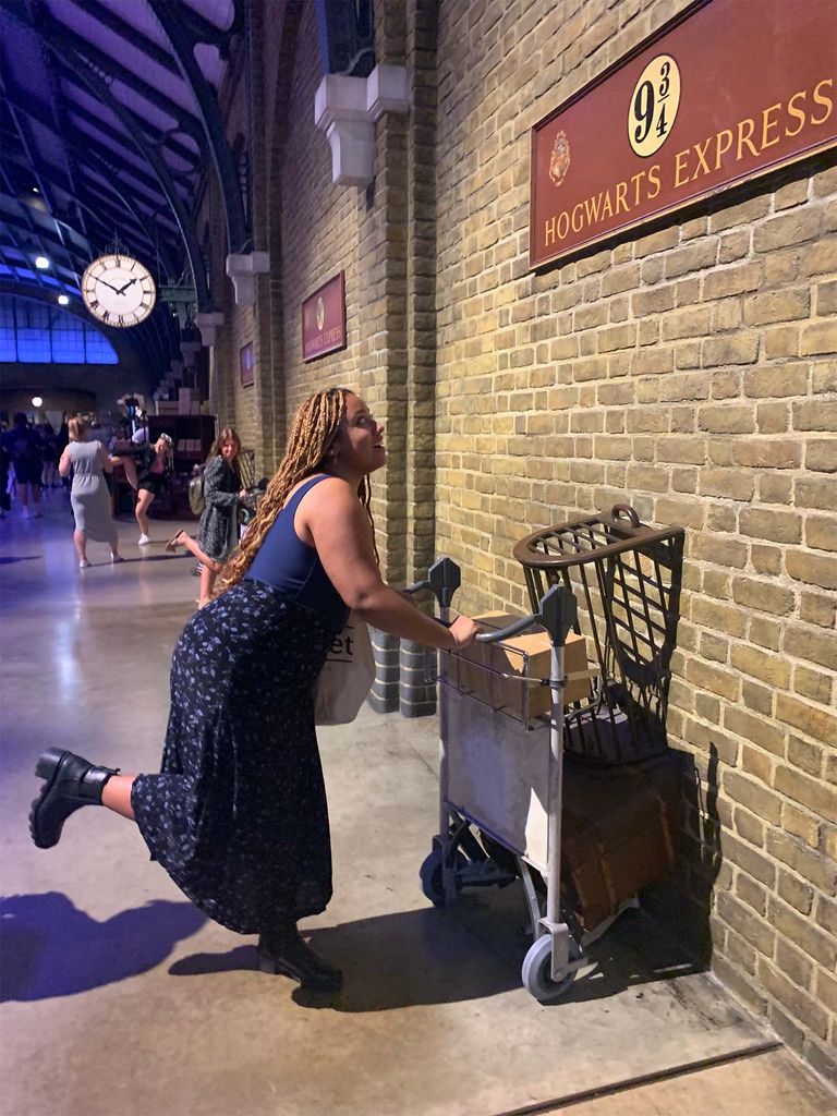 A CGS London Student pushes a cart through a wall at Platform 9 3/4, a Harry Potter landmark