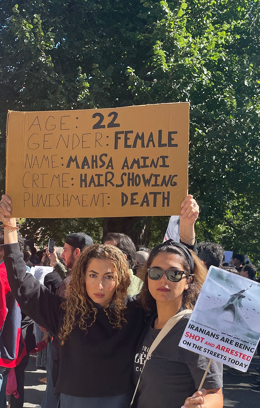 Photo: Two women hold up signs at a protest in Boston. One large sign written on cardboard reads "Age: 22. Gender: Female. Name: Mahsa Amini. Crime: Hair showing. Punishment: Death".