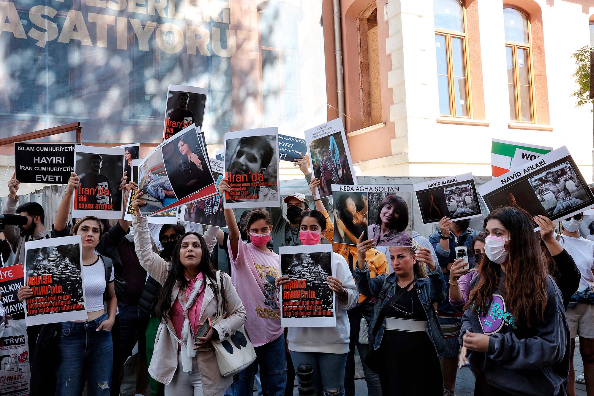 Photo: People hold signs and chant slogans during a protest over the death of Iranian Mahsa Amini outside the Iranian Consulate in Istanbul, Turkey, on September 26, 2022. A group of women, most not wearing hijabs, hold signs supporting Amini and protesting her death.