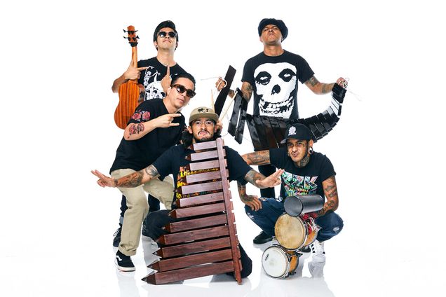 Photo of Mexican group Son Rompe Pera posting with their musical instruments. The group is comprised of fiven youngish men of color, all of them with arm tattoos. Two hold instruments that look like xylophones , one holds a small guitar, another a set of handle held drums.