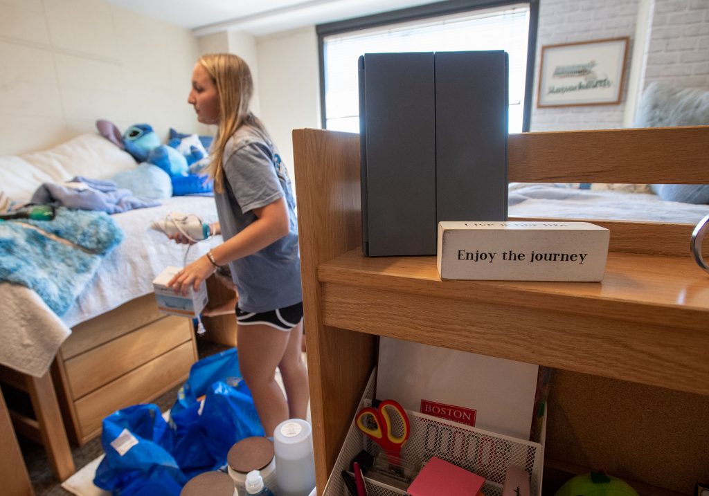 Photo: Allison Zeoli (CFA’26) in her Claflin Hall dorm room during move in. A young white woman stands in the middle of a packed room as she starts to unpack.