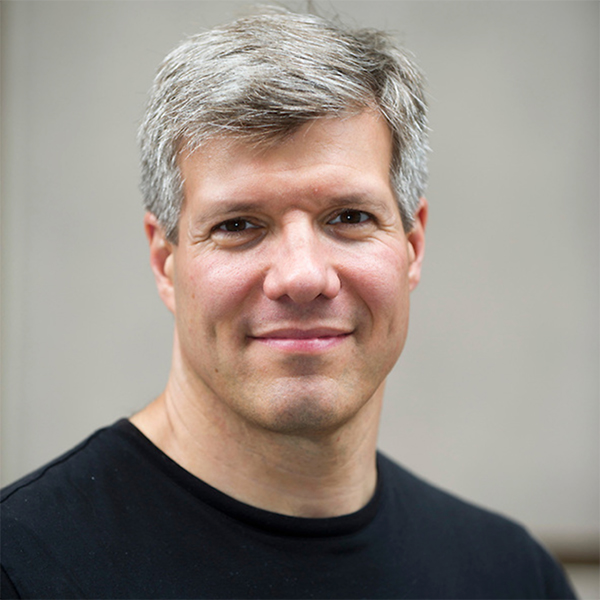 Photo: Headshot photo of Ed Damiano. A white man with silver hair and wearing a black shirt smiles for the camera.