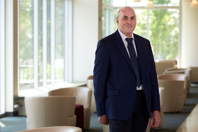 Portrait of Doctor Drew Weissman standing in a lobby wearing a navy blue suit.