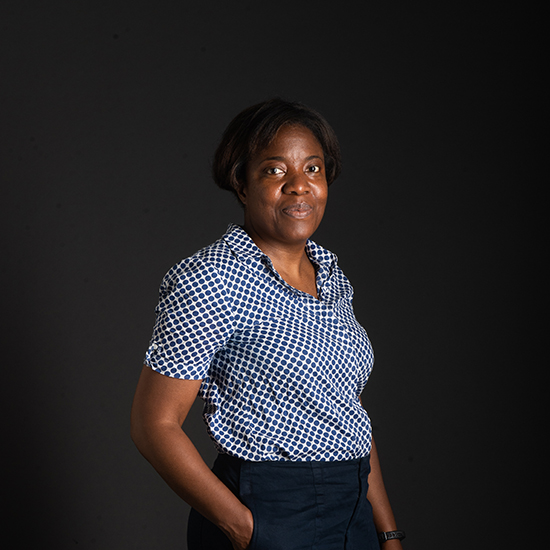 a photo of SPH assistant professor Junenette L. Peters as she poses with one hand in pocket in front of a black backdrop.
