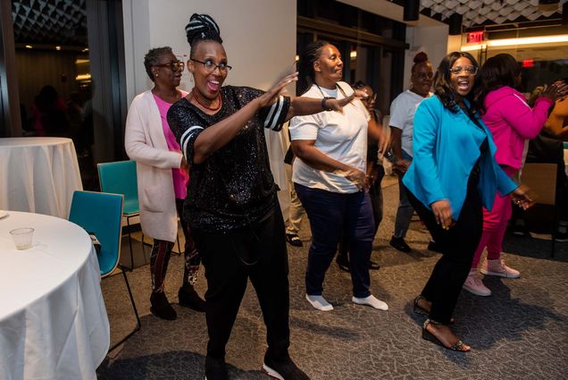 Photo: MC Amanda Merrick, dressed in black, dances with other members during the opening reception for Mothers for Justice & Equality's seventh annual national conference Oct 12 at Howard Thurman Center. A group of Black women gather and dance the cha cha slide.