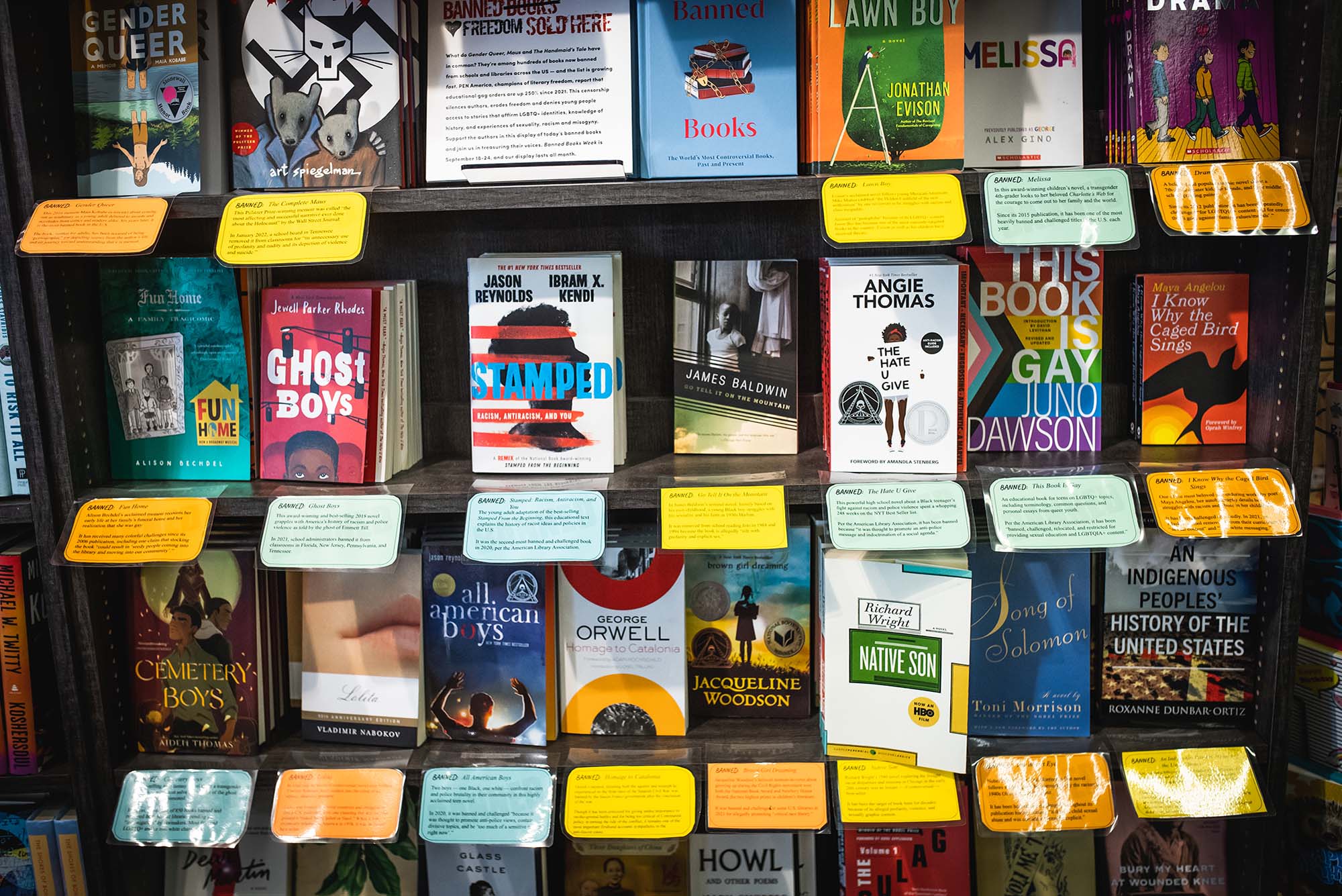 A photo at Brookline Booksmith where banned books are available for purchase. The books displayed have cards explaining when, where, and why the book was banned.